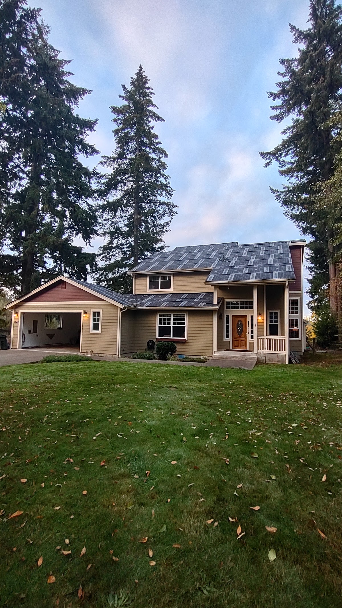 A completed roof with new dark shingles on a home at dusk